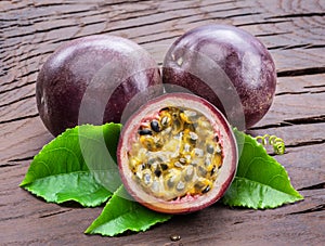 Dark purple passion fruits and it's half with seedly interior on wooden table