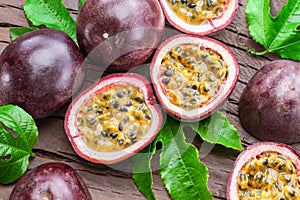 Dark purple passion fruits and it's half with seedly interior on wooden table