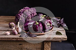 Dark purple peppers, cauliflower with leaves of basil and garlic