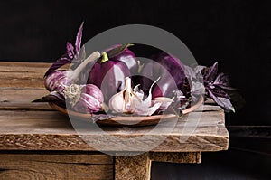 Dark purple peppers with leaves of basil and garlic