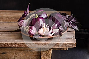 Dark purple peppers with leaves of basil and garlic