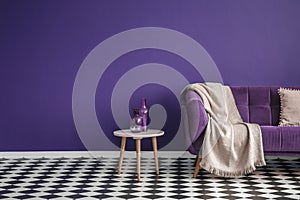 Dark purple sofa with a blanket beside a small table with bottle