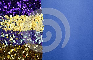 Dark purple, yellow, blue and golden glitter on the trendy blue background. Empty space for design