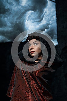 Dark queen of the ghost in a dark castle collapsed, visible destruction of the castle wall and dark storm clouds