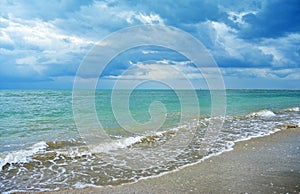 Dark Rain Clouds over turquoise Sea and sand Beach