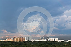 Dark rainy clouds in sunset sky over city