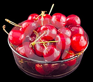 Dark-Red cherries in a brown transparent bowl, isolated, black background