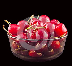 Dark-Red cherries in a brown transparent bowl, isolated, black background