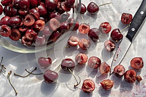 Dark red cherries cut into halves on white cutting board