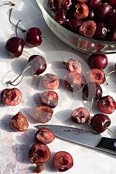 Dark red cherries cut into halves on white cutting board