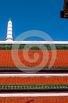 Dark red and green roof and white spire against a dark blue sky at Grand Palace, Thailand