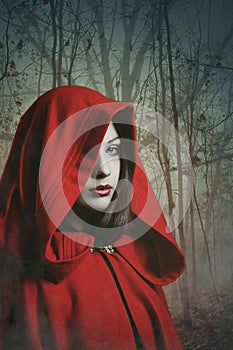 Dark red hooded woman in a misty forest