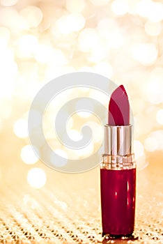 Dark red lipstick on golden Christmas, New Years and Valentines Day holiday glitter background, make-up and cosmetics product for