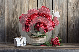 Dark red peonies in a decorated glass jar photo