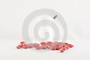 Dark red and pink pills spilling from a white plastic bottle wit