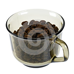 Dark roasted coffee beans in glass cup isolated on white