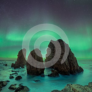 Dark rock against northern lights landscape with stars, starry sky with polar lights. Beautiful massive northern lights