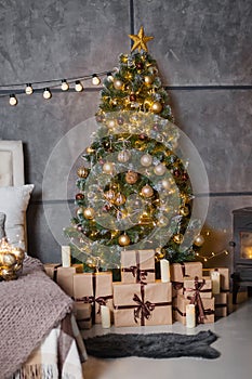 A dark room with a bed and many decorations and lights, a Christmas tree with gifts under it, a gray wall