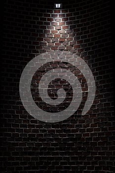 Dark room wall with ceiling light background. Old, weathered red and grey brick stone wall. Low key, scary, moody space