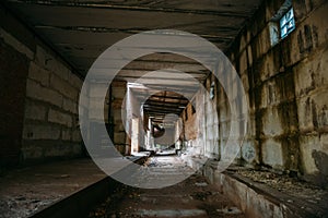 Dark scary corridor in abandoned industrial ruined brick factory, creepy interior, perspective