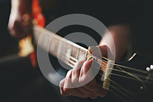 Dark scenery with woman playing chord on electric guitar