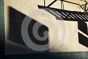 Dark shadows of fire escape and sign on side of stucco building