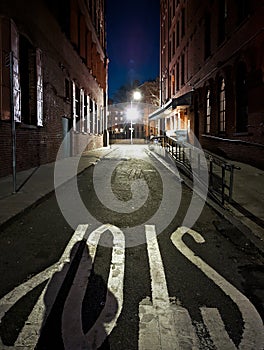 Dark side street at night with light shining in the distance in New York City