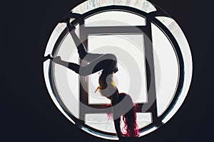 The dark silhouette of a beautiful woman on the background of the round window. yoga, acrobatics.