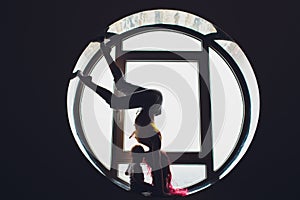 The dark silhouette of a beautiful woman with child on the background of the round window. yoga, acrobatics.