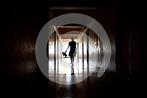 A dark silhouette of a child with a Teddy bear. One child with a dark long corridor. Spooky scary hallway. The house is haunted.