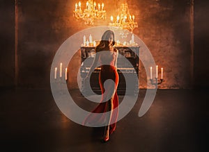 Dark Silhouette fantasy lady gothic beautiful woman blond hair in red dress walks in luxurious room black piano candles