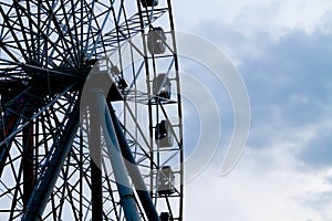 The dark silhouette of the Ferris wheel against the blue sky in the evening in the city