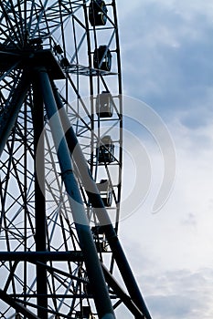 The dark silhouette of the Ferris wheel against the blue sky in the evening in the city