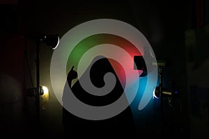 A dark silhouette holding up a voting mark against a backdrop of vibrant stage lighting effects