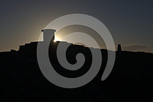 Dark silhouette of malvern hills toposcope and trig point at sunrise