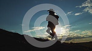 Dark silhouette of man in hat going uphill enjoying hiking