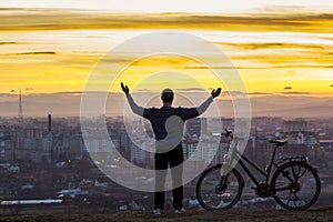 Dark silhouette of a man standing near a bicycle with the night