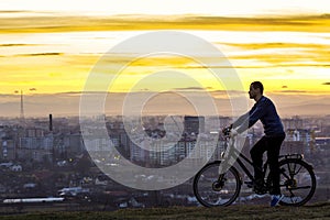 Dark silhouette of a man standing near a bicycle with the night