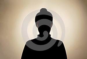 Dark silhouette of young girl on gray background, concept of anonymity. photo