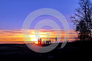 Dark silhouettes of people on winter sunset background