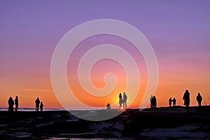 Dark silhouettes of people on winter sunset background