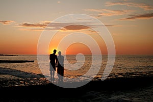 dark silhouettes of young people on the background of the sunset on the sea
