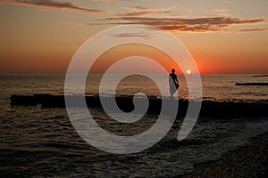 dark silhouettes of young people on the background of the sunset on the sea