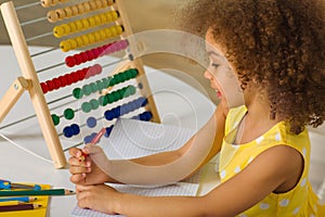 A dark-skinned African-American girl is ready for a math and arithmetic lesson with an abacus