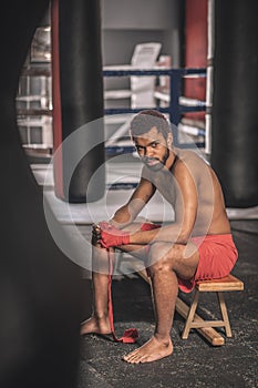 Dark-skinned athlete typing his hands with a red bandage