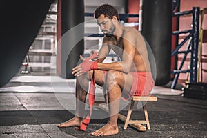 Dark-skinned athlete typing his hands with a red bandage