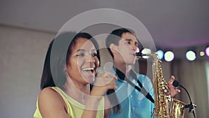 Dark-skinned black woman singer and thin saxophone player performing on stage.