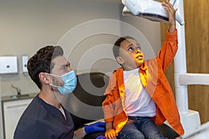 Dark-skinned boy loking interested in dental lamp