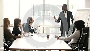 Dark-skinned businessman giving presentation to partners at meeting in boardroom