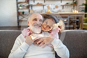 Dark-skinned girl with curly hair hugging her grandad and looking peaceful